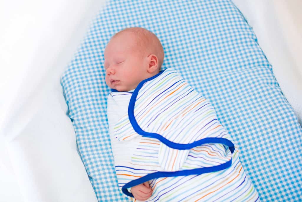 baby sleeping in crib or bassinet swaddled