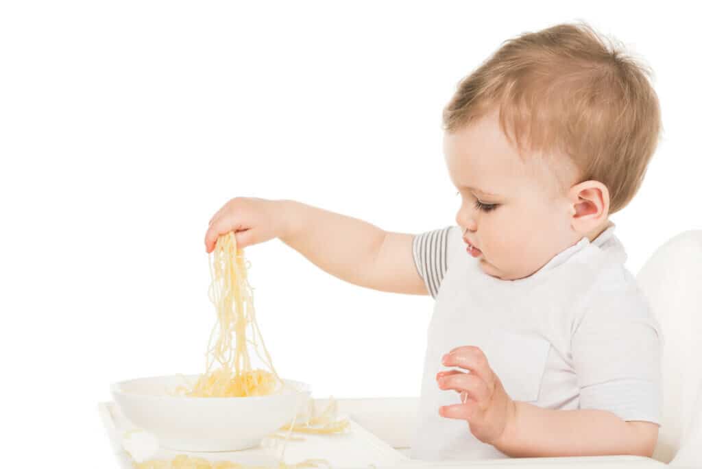 baby led weaning baby or toddler grabbing spaghetti to eat